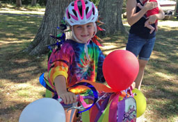 A girl poses with her bicycle, decorated with balloons for parade