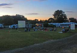 open field at dusk with large screen for nighttime movies