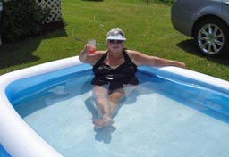 Elderly woman raises her beverage glass in her inflatable pool