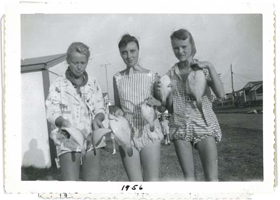 Three teenage girls wearing  bloomer rompers bathing suits with pose with fish, 1956 on margin